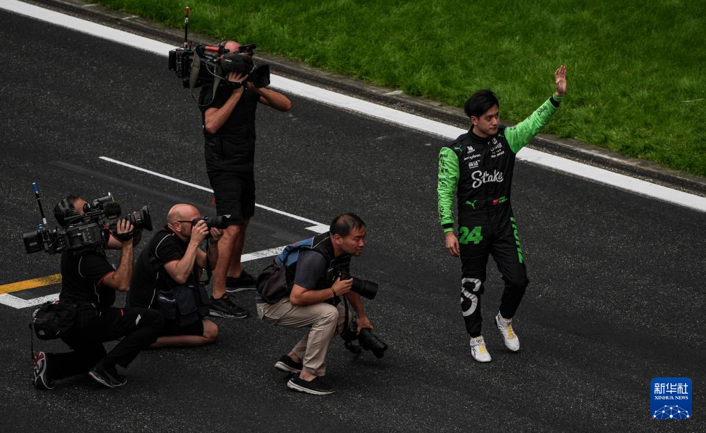 4月21日，索伯车队中国车手周冠宇（右一）在比赛后向不雅众挥手致敬。新华社记者  夏一方摄