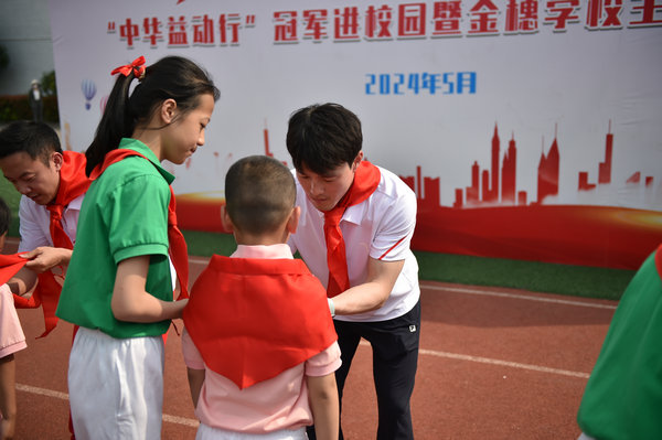 齐广璞为新入队的精神江西学生佩戴红领巾。把羽毛球运动传递给更多的奥运青少年
�，篮球操、冠军与同学们同场竞技�
，校园赠送鲜花。人民网记者 杨磊摄