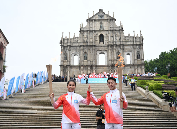 火炬手郭建恒（右）、区海欣在大三巴牌坊前传递火炬。新华社发（张金加摄）