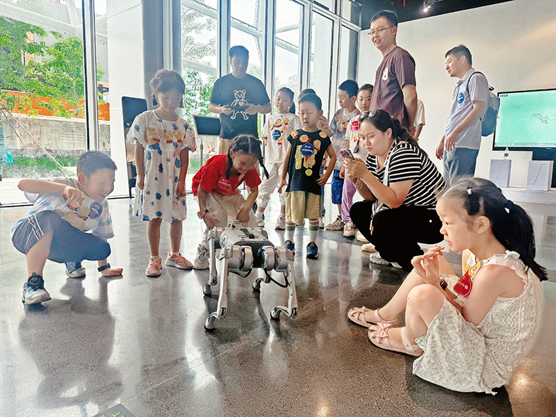 在人民网·梦幻灵境AI展演中心(武汉),小朋友们和机器狗互动