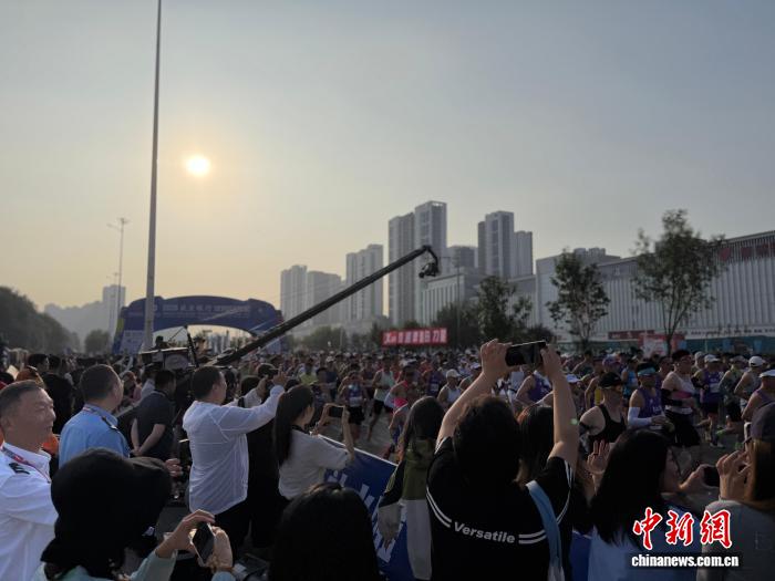 9月6日清晨7时，2026沈阳马拉松鸣枪起跑。22000名跑者齐聚沈阳奥体中心南门，迎着初秋晨光，驰骋于浑河两岸，以奔跑拥抱沈城秋日。赛事吸引了人们在赛道旁拍照。胡文熙 摄