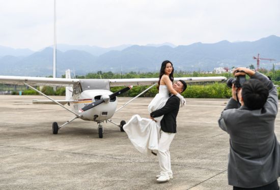 2024年5月3日，在重庆龙兴通用机场，一双行将乘坐轻型剖判类飞机的新东谈主在登机前合影。新华社记者 王全超 摄