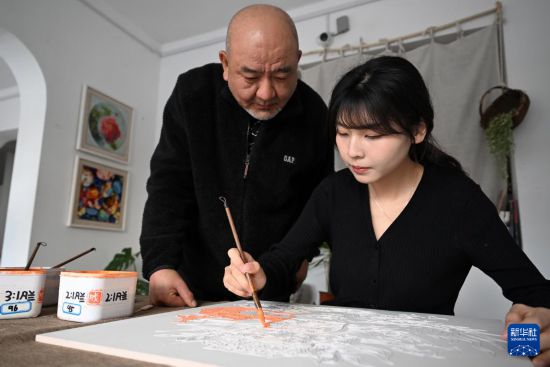 12月3日，在洛阳花城好意思陶使命室，后果（右）在父亲成永胜的率领下施釉。