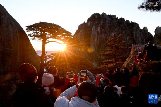 　2025年1月1日，游客在安徽黄山风景区迎客松景点观赏日出。