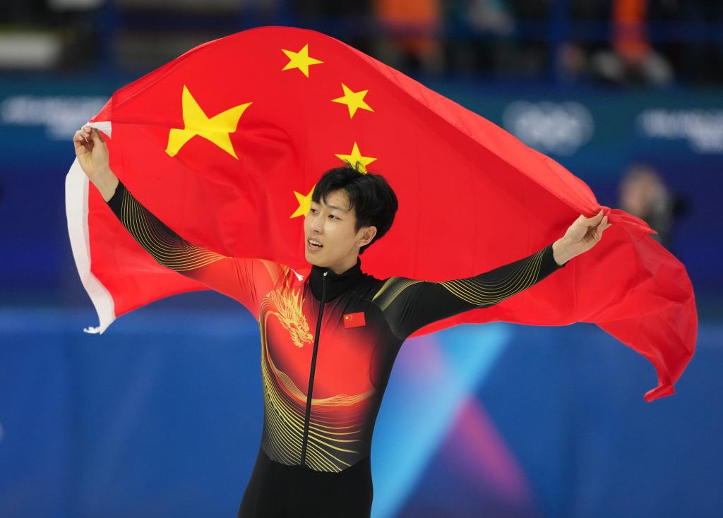 2月12日,孙龙在比赛后身披国旗庆祝。当日,米兰-科尔蒂纳冬奥会短道速滑男子1000米A组决赛在意大利米兰举行,中国选手孙龙获得银牌。新华社记者 薛宇舸 摄